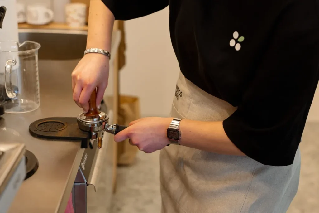 Barista spaudžia maltą kavą į espreso rankenėlę Brastos Sodo kavinėje